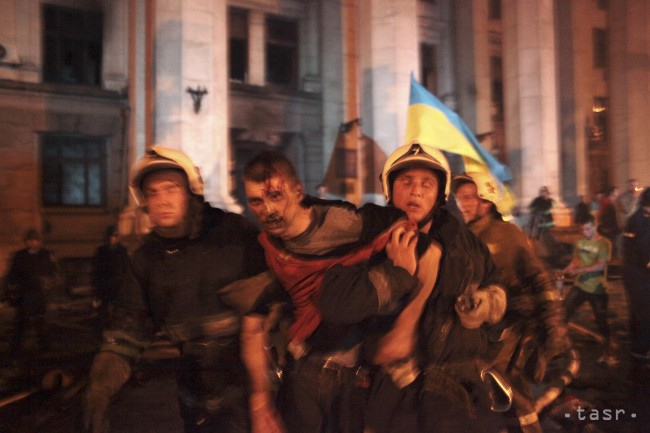 Hasiči odnášajú zraneného muža z horiacej budovy domu odborov v juhoukrajinskom meste Odesa 2. mája 2014. 