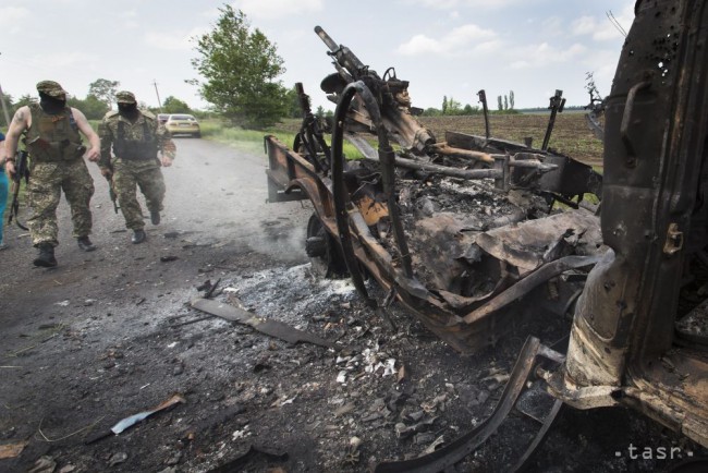 Dvaja proruskí separatisti kráčajú k zničenému ukrajinskému obrnenému vozidlu APC počas bojov medzi proruskými separatistami a vládnymi jednotkami v dedine Oktjabrskoje, 20 km od Kramatorska na východe Ukrajiny 15. mája 2014.