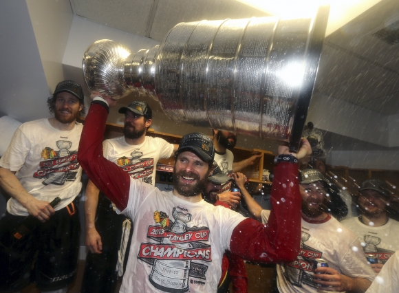 Radosť Michala Handzuša so Stanleyho pohárom nad hlavom po šiestom finálovom zápase NHL, v ktorom Blackhawks zvíťazili na ľade Bostonu 3:2.