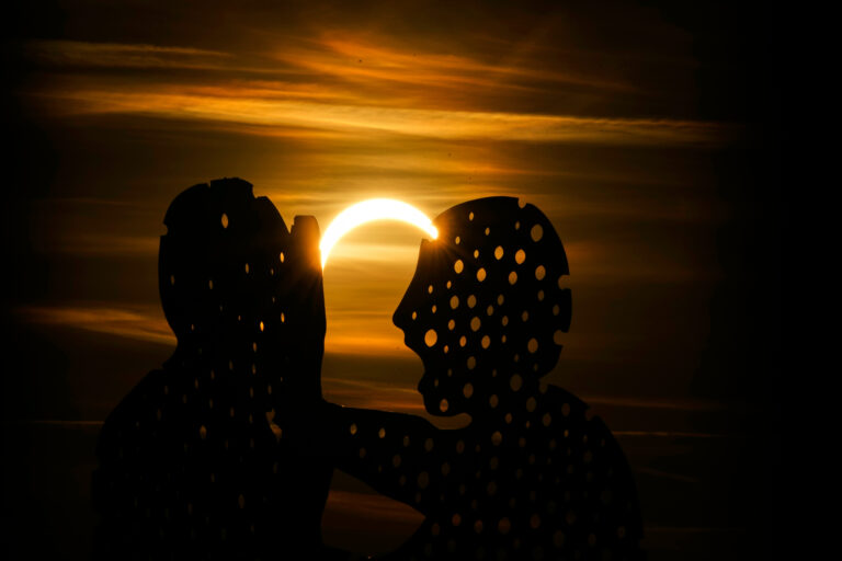 Čiastočné zatmenie zachytené cez siluety sochy Molecule Man v Berlíne. Foto: SITA/AP